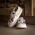 Load image into Gallery viewer, A pair of Camp Shoes in cow print sitting on the floor.