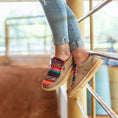 Load image into Gallery viewer, A girl sitting on a gate with her feet dangling and wearing a pair of serape Camp Shoes.