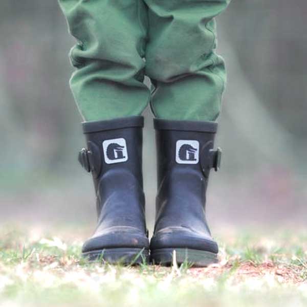 Legs and feet of a kid that is wearing black Gator waders rain boots