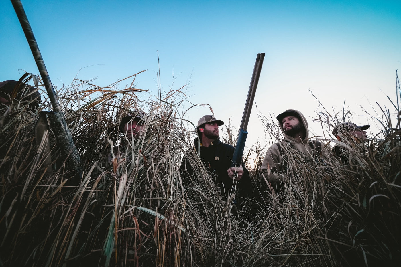 A group of guys standing in a hunting blind. 