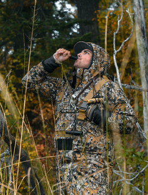 Picture of a guy blowing on a duck call looking at the sky wearing Gator Waders.